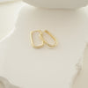 Gold hoop earrings on a white ceramic surface