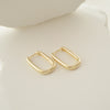 Gold hoop earrings on a light beige surface