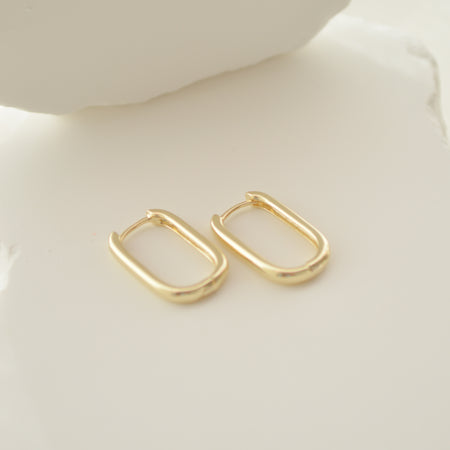 Gold hoop earrings on a light beige surface
