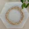 A gold-filled bracelet with a mix of rice and round beads, displayed on a marble surface.