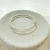 This image features a sleek and elegant Silver Bar Bracelet, showcased on a white, textured surface. The bracelet consists of a sturdy, pre-stretched elastic cord that ensures minimal stretch, maintaining the integrity and style of the piece.