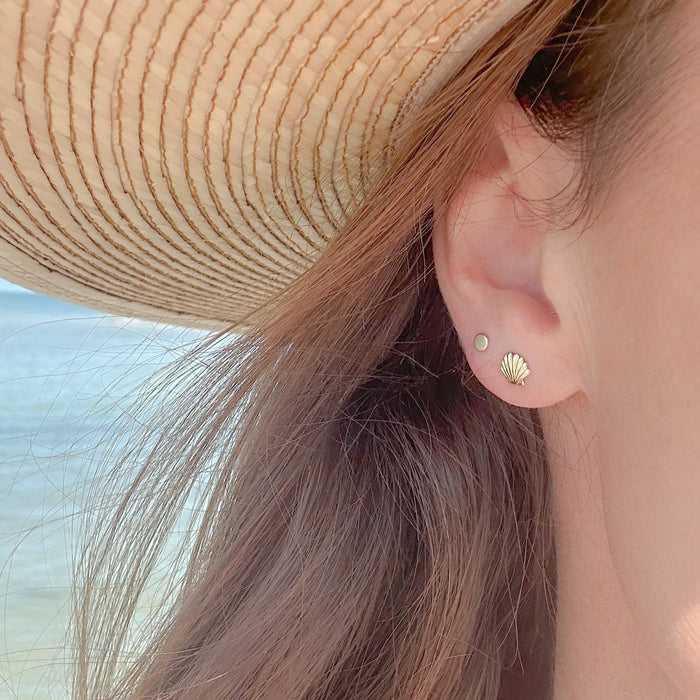 Woman's ear with seashell earrings and sun hat